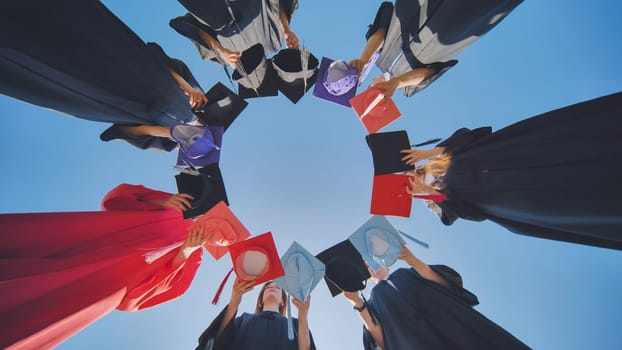 College graduates make a circle shape out of their colorful hats