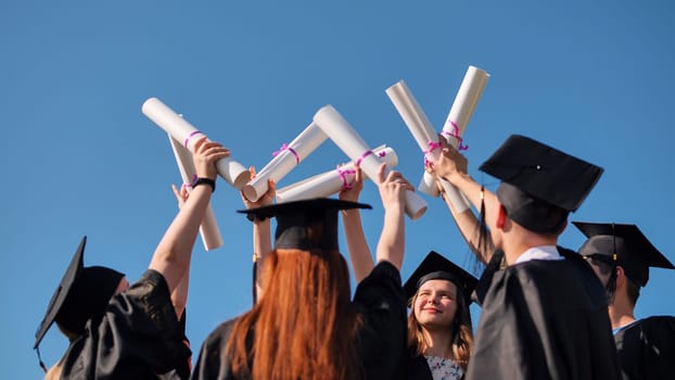 College graduates with caps tie their diplomas together