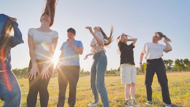 Funny jolly friends dancing in the city meadow in the evening