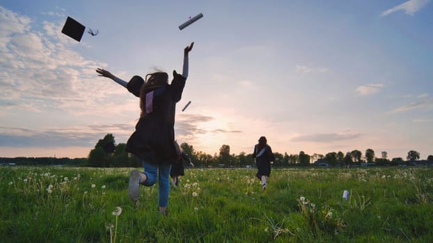 Graduation girl running in the background of the sunset and throwing her hat and notebooks