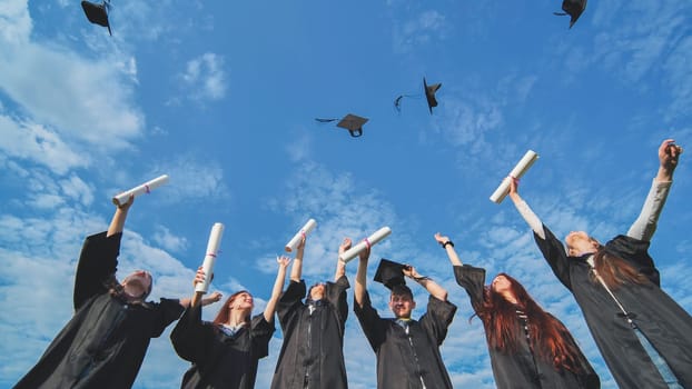 Silhouettes of Happy college graduates tossing their caps up at sunset.