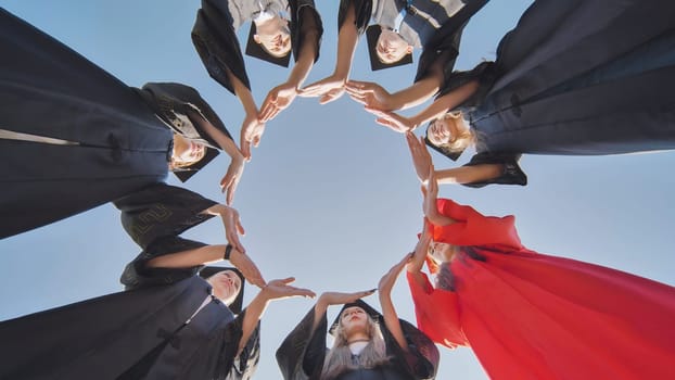 College graduates make a large circle from their hands