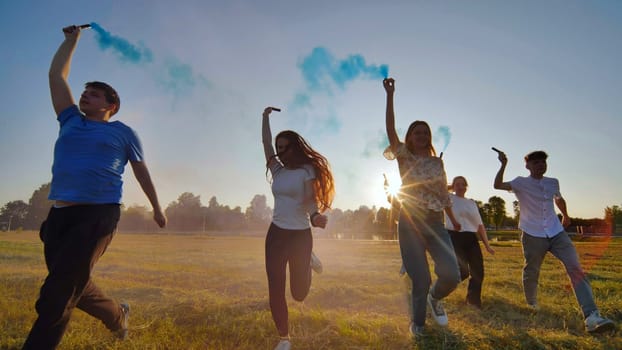 A group of friends spraying multi-colored smoke at sunset