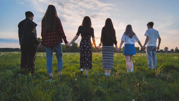 A group of friends stand in a row at sunset