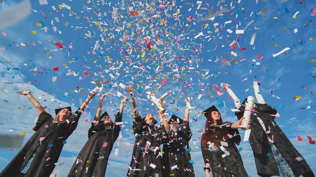 Happy graduates throw colorful confetti against a blue sky