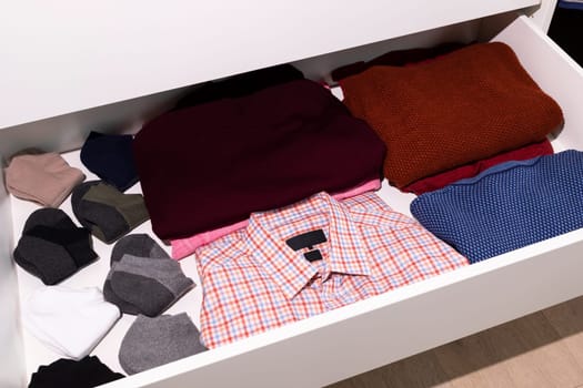 Top View Of Shelf With Male Clothes, Outfit in Drawer Of Closet. Folded Fresh Dress Shirt, Sweaters, Socks. Man's Clothing Storage. Wardrobes And Cabinetry. National Clean Your Room Day. Horizontal