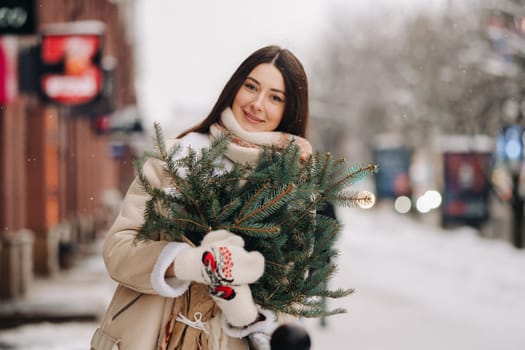 Girl with long hair in winter on the street with a bouquet of fresh spruce branches.