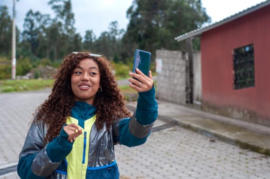 pretty latina millennial girl talking on her cell phone to her followers while showing her rural adventures. world influencer day. High quality photo