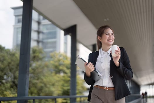 Young Asian Businesswoman happy confident walking on skywalk while going to working in city.