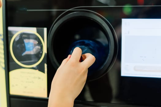 Reverse vending recycling machine that dispenses cash. Man hand puts plastic bottle to machine