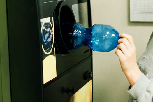 Reverse vending recycling machine that dispenses cash. Man hand puts plastic bottle to machine