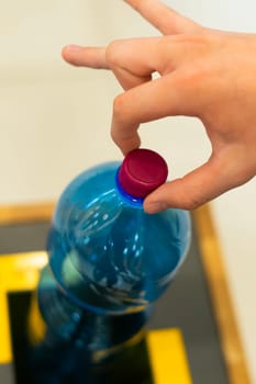 Selective focus close up hand throwing empty plastic bottle in the recycling garbage trash or bin