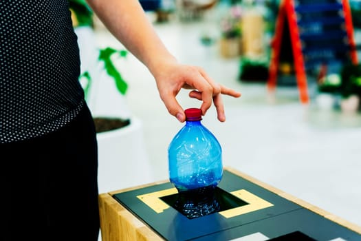 Selective focus close up hand throwing empty plastic bottle in the recycling garbage trash or bin