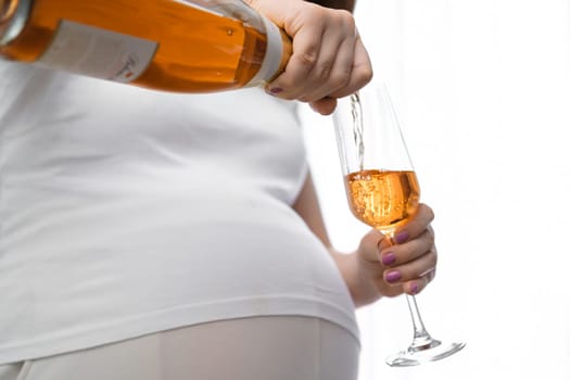 Irresponsible pregnant woman pours wine into the glass. Alcohol during pregnancy