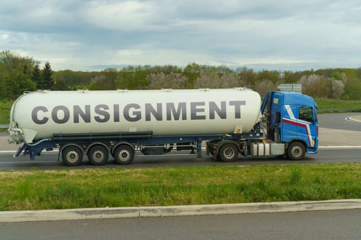 On a tank truck driving along the road there is an inscription - consignment. Logistics concept.