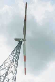 Wind turbine for generating electricity outdoors against the background of the sky and clouds. Concept of alternative energy sources