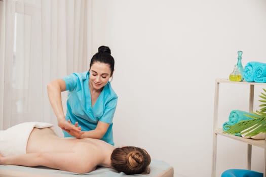 A female masseur massages the client's back in the office