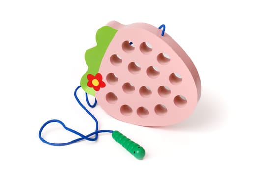 Pink wooden children's educational toy in the shape of a strawberry with a funny worm on a rope, isolated on white background.
