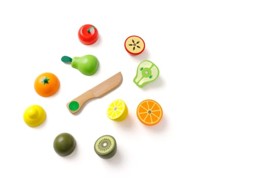 Top view on educational kid's set of toys in the form of cut fruits and a wooden knife, isolated on white background, copy space.