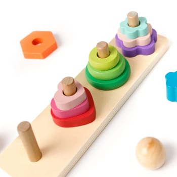 Close-up of Montessori wooden kids's puzzle toy with colorful blocks of different shapes in the shape of 4 pyramids isolated on white background.