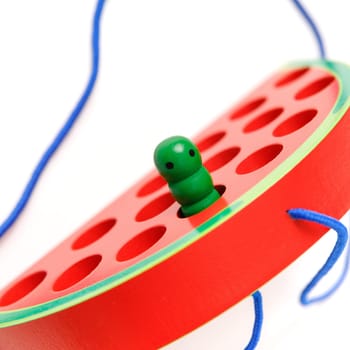 Kid's wooden toy in the shape of a watermelon with a funny worm on a rope, toy for developing fine hand motor skills.