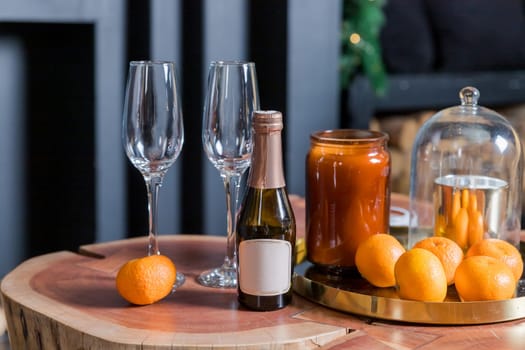 Two glasses of champagne and tangerines on a table against blurred christmas background with christmas lights. New year celebration party