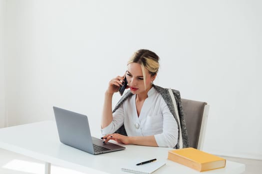 woman in office working on laptop talking on phone