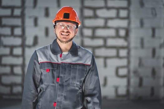 Portrait of a happy laughing bearded worker in overalls at a construction site.