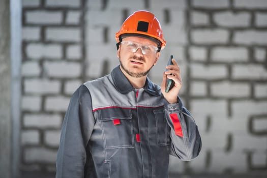 A professional worker at a construction site using a smartphone is always in touch with the customer or foreman.