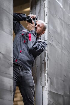 Industrial photographer in overalls takes pictures at a facility under construction.