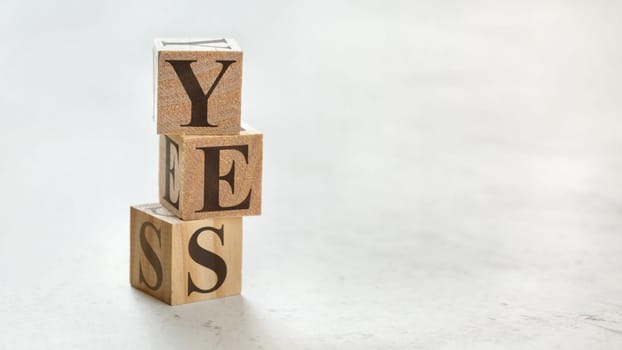 Pile with three wooden cubes - word YES on them, space for more text / images at right side.