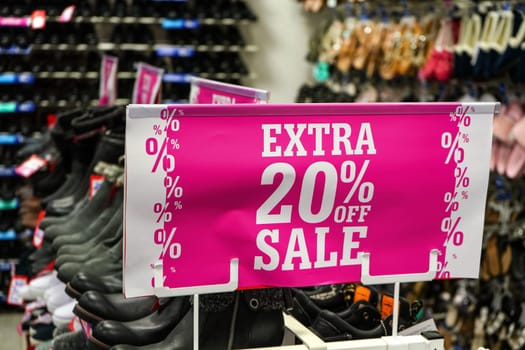 Bright pink Extra 20 percent off sale sign at shoe shop.