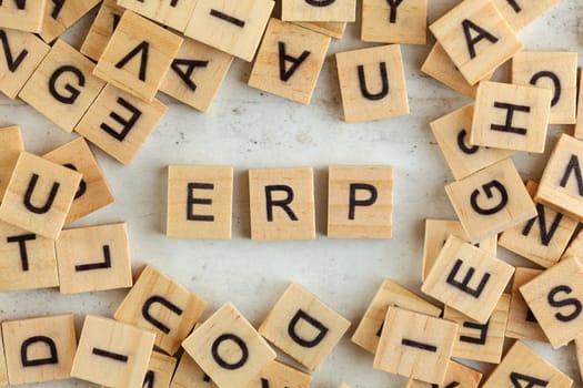 Top down view, pile of square wooden blocks with letters ERP (stands for Enterprise resource planning) on white board. 