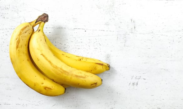 Bunch of bananas on white working board, space for text right