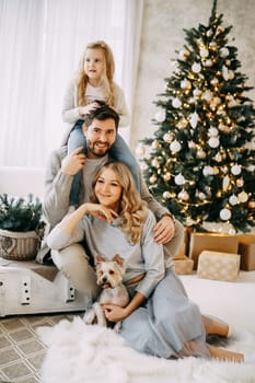 Happy family: mom, dad and daughter. Family in a bright New Year's interior with a Christmas tree