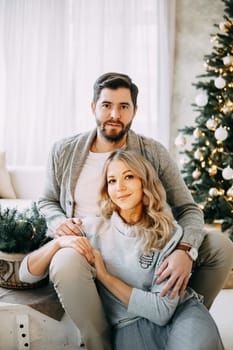 Happy family: mom, dad and pet. Family in a bright New Year's interior with a Christmas tree.