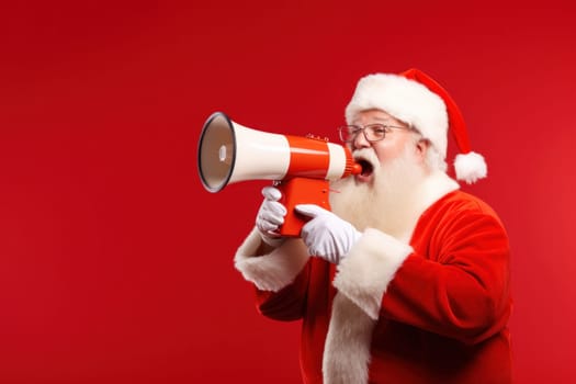 Santa Claus with megaphone on red background. Announcement or advertising of Christmas sales, announcement of winners.