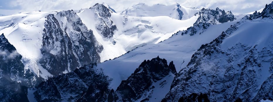 Highlands cliffs, snow-capped peaks of mighty mountains in the clouds, a stunning view from above