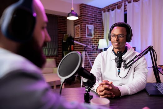 Podcast presenter having live conversation with man, recording discussion for audience on internet entertainment show. Influencer enjoying chat with guest, broadcasting at home