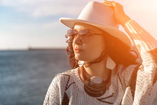 Portrait of a curly haired woman in a white hat and glasses on the background of the sea