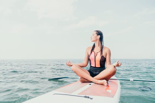 Woman sup yoga. Happy young sporty woman practising yoga pilates on paddle sup surfboard. Female stretching doing workout on sea water. Modern individual female outdoor summer sport activity