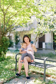 Smiling mother with little girl talking on video call on smartphone. High quality photo