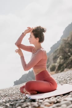 Young woman with long hair in white swimsuit and boho style braclets practicing outdoors on yoga mat by the sea on a sunset. Women's yoga fitness routine. Healthy lifestyle, harmony and meditation