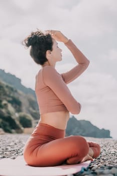 Young woman with long hair in white swimsuit and boho style braclets practicing outdoors on yoga mat by the sea on a sunset. Women's yoga fitness routine. Healthy lifestyle, harmony and meditation