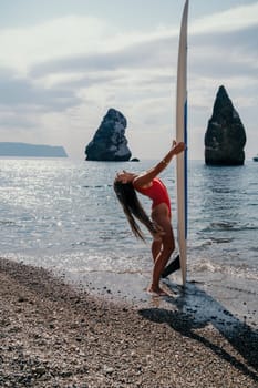 Close up shot of beautiful young caucasian woman with black hair and freckles looking at camera and smiling. Cute woman portrait in a pink bikini posing on a volcanic rock high above the sea