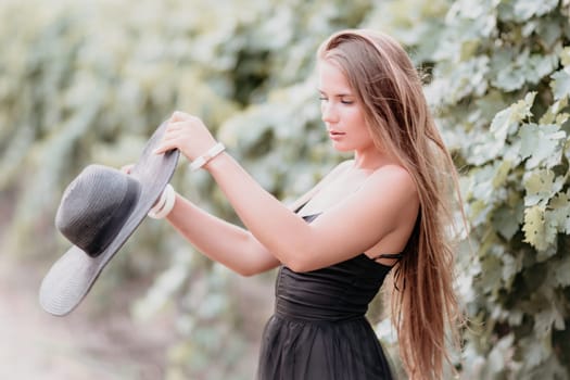 Woman at autumn winery. Portrait of happy woman holding glass of wine and enjoying in vineyard. Elegant young lady in hat toasting with wineglass smiling cheerfully enjoying her stay at vineyard