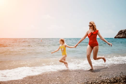 Happy loving family mother and daughter having fun together on the beach. Mum playing with her kid in holiday vacation next to the ocean - Family lifestyle and love concept.