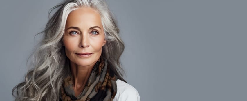 Elegant, smiling, elderly, chic, woman with gray long hair and perfect skin, on a gray background, banner. Advertising of cosmetic products, spa treatments, shampoos and hair care products, dentistry and medicine, perfumes and cosmetology for women.