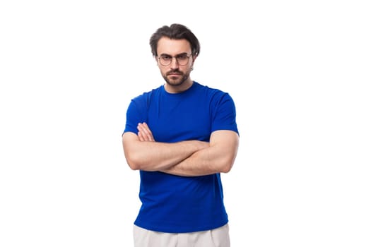 portrait of a young caucasian brunette man with a stylish hairstyle and beard in a blue t-shirt with a mockup on a white background with copy space.