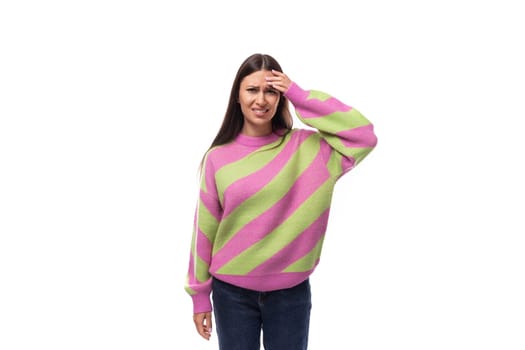 upset young brunette woman in a striped pink sweater on a white background with copy space.